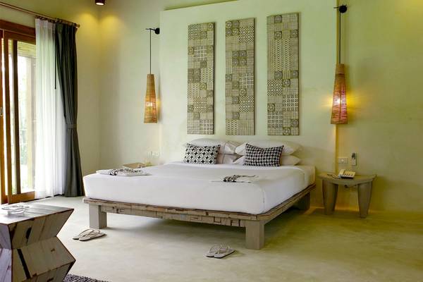 Schlafzimmer im Bangsak Village Hotel mit einem großen Bett, drei Wandhängen und einem Tisch.