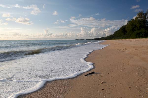 Strand mit sanften Wellen und blauem Himmel mit einigen Wolken