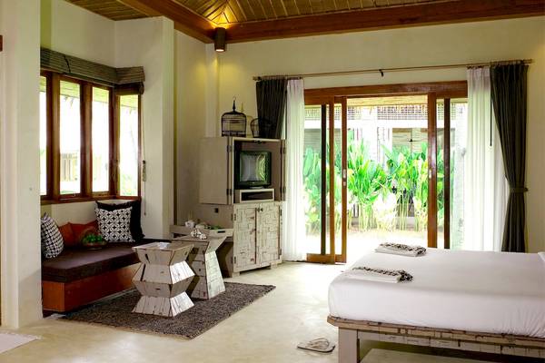 Bangsak Village Hotel Zimmer mit Bett, Couch, Fernseher und offenem Balkon.