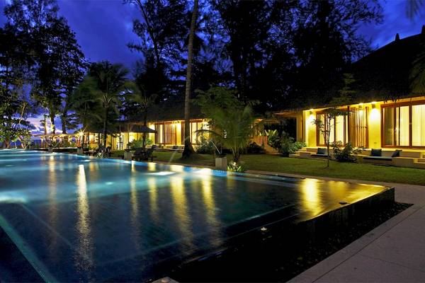 Außenbereich des Bangsak Village Hotels mit Swimmingpool bei Nachtbeleuchtung.