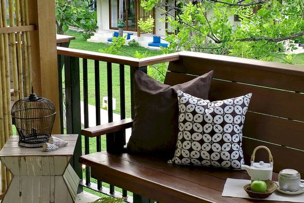 Ein Sofa auf einer Terrasse mit grünem Hintergrund und einem Tisch mit Dekor.