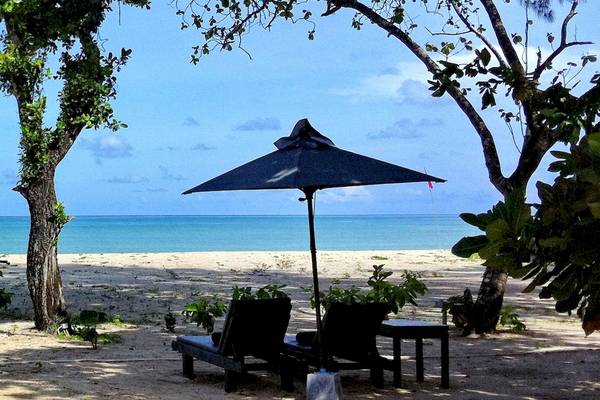 Strand mit Liegen unter einem schwarzen Sonnenschirm im Bangsak Village.