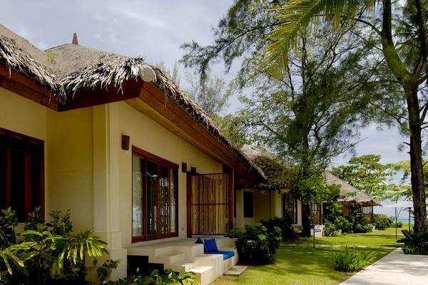 Außenansicht des Bangsak Village Hotels mit blauen Kissen auf der Veranda und umliegender Grünanlage
