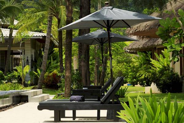Außenbereich des Bangsak Village Hotels mit Lounge-Stühlen unter Schirmen.
