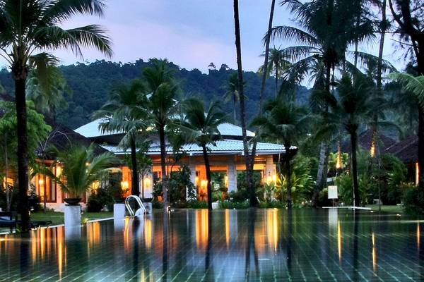 Der Pool des Bangsak Village Hotels bei Nacht mit Palmen und Berg im Hintergrund.