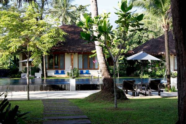 Außenbereich des Bangsak Village Hotels mit Swimmingpool, Sonnenliegen und Schirmen.