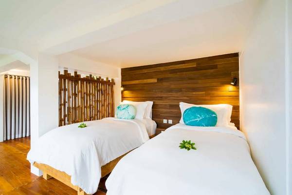 Zwei Betten mit weißen Laken und blauen Kissen in einem Zimmer der TreeHouse Villas Koh Yao.