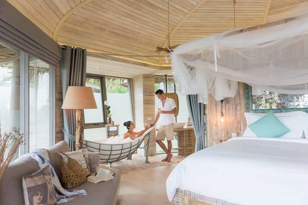 Schlafzimmer in TreeHouse Villas Koh Yao mit Badewanne, Bett und modernem Design.