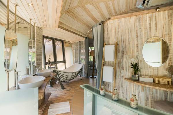 Das Badezimmer der Treehouse Villas Koh Yao mit einer Badewanne, zwei Waschbecken und einem Spiegel.