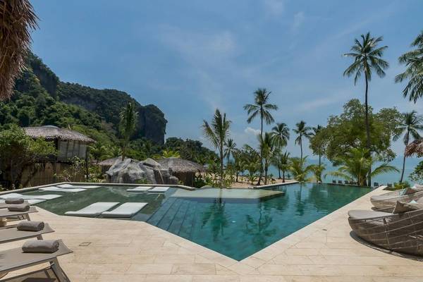 Außenpool der TreeHouse Villas Koh Yao mit Liegen und Blick auf das Meer.