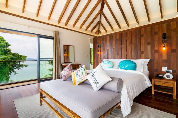 Schlafzimmer mit Bett, Kissen, Nachttisch und Meerblick in TreeHouse Villas Koh Yao