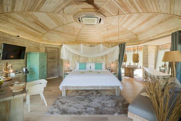 Innenansicht eines Schlafzimmers in den TreeHouse Villas Koh Yao mit einem Rundbett, weißem Moskitonetz und grünen Kissen.
