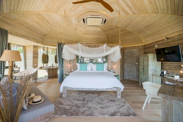 Innenansicht eines Schlafzimmers in den TreeHouse Villas Koh Yao mit Rundbett, hängendem Moskitonetz und Holzelementen.