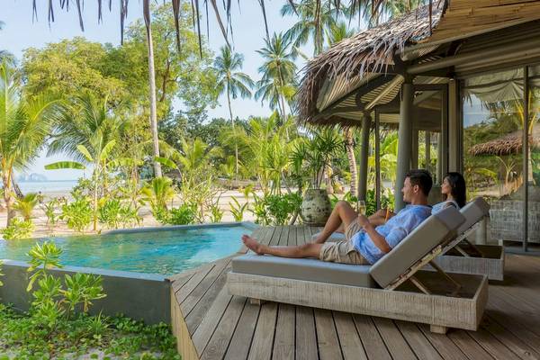 Paar auf Loungesesseln neben dem Pool der TreeHouse Villas Koh Yao