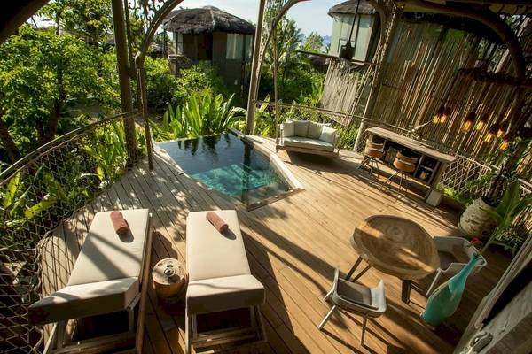 Terrasse der TreeHouse Villas Koh Yao mit Pool, Liegestühlen und Tisch.