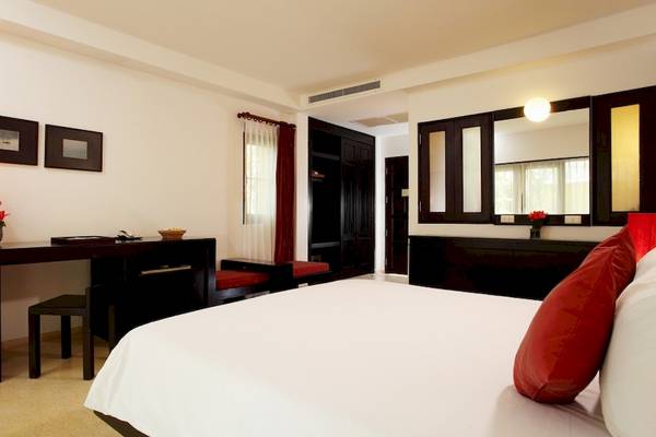 Schlafzimmer im Haadson Resort mit weißem Bett, rotem Kissen, Schreibtisch und Lampe.