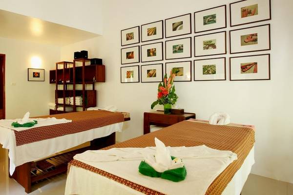 Massageraum im Haadson Resort mit zwei Massagetischen und gerahmten Bildern an der Wand.
