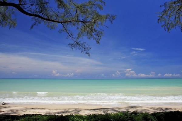 Ausblick auf einen weißen Strand mit blauem Himmel und grünem Meer