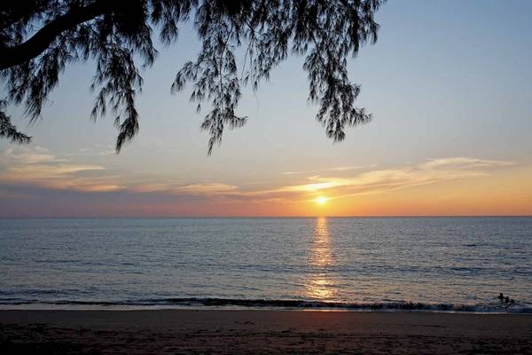 Sonnenuntergang am Strand vor dem Haadson Resort mit einer Person im Wasser.