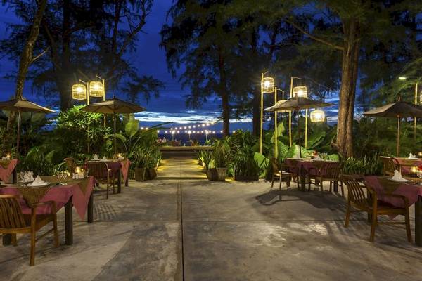 Außenbereich des Haadson Resorts bei Nacht mit gedeckten Tischen und hängenden Laternen.