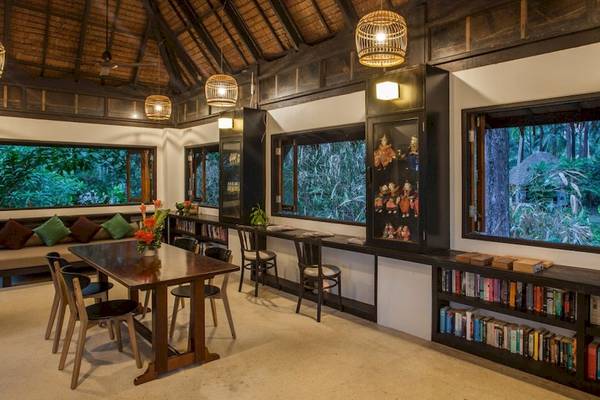 Innenraum der Bibliothek im Haadson Resort mit großen Fenstern, Holzmöbeln und Bücherregalen.