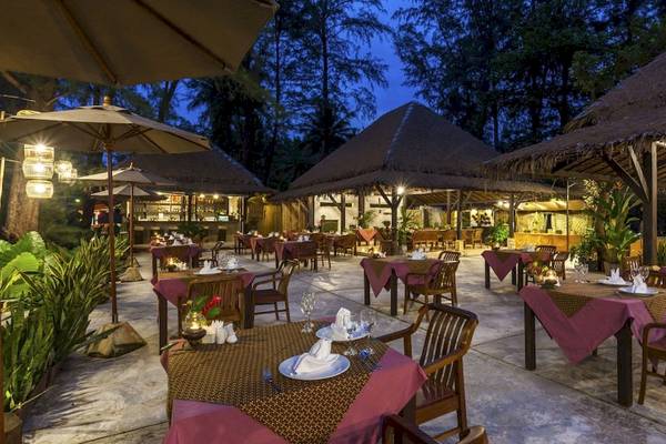 Außenbereich des Haadson Resorts mit Tisch und Stühlen, umgeben von Pflanzen und beleuchteten Dächern.