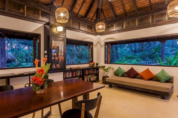 Wohnbereich des Haadson Resorts mit großen Fenstern, Couch, Bücherregal und Blumenvase.