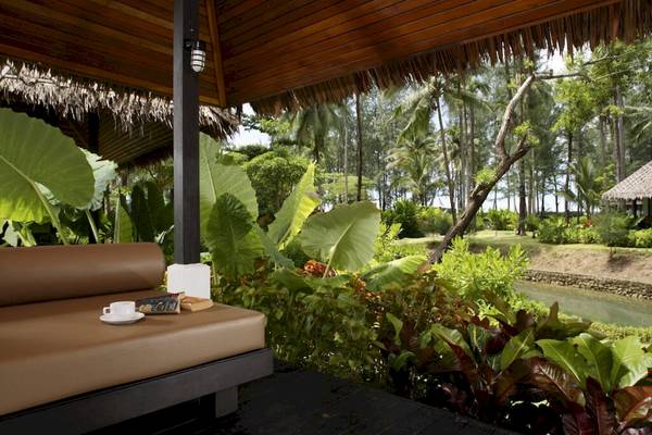 Außenbereich des Haadson Resorts mit einem braunen Sofa, Büchern und einer Tasse Kaffee.