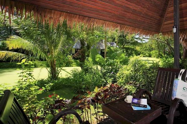 Sitzbereich im Garten des Haadson Resorts mit einer Tisch und Stühlen, umgeben von Pflanzen und Bäumen.
