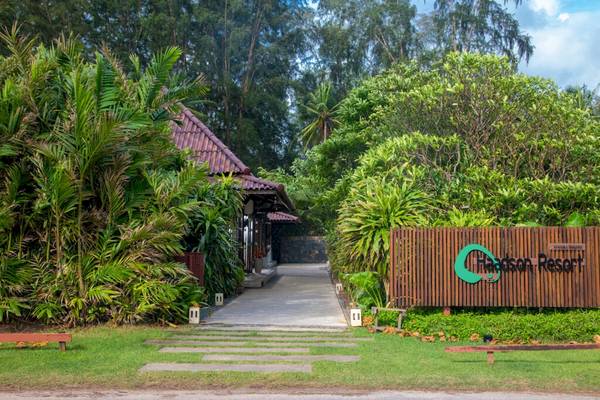 Foto des Eingangs zum Haadson Resort, umgeben von grünen Pflanzen und Bäumen.