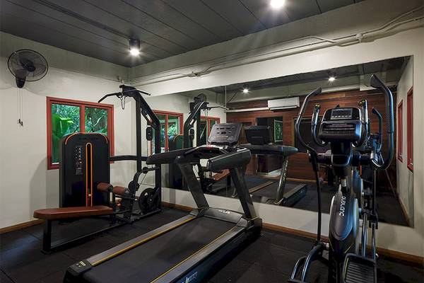 Fitnessraum im Khaolak Paradise Resort mit Laufband, Hanteln und einem großen Spiegel.