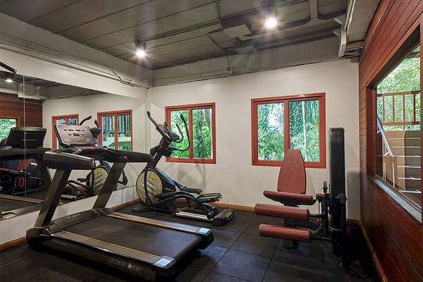 Fitnessraum im Khaolak Paradise Resort mit Laufband, Rudergerät und Fenstern.