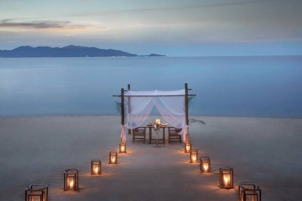 Dinner-Setup am Strand des Santiburi Koh Samui mit Tisch, Stühlen und Laternen