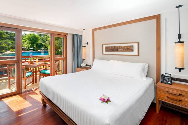 Innenansicht eines Hotelzimmers im Santiburi Koh Samui mit Blick auf einen Swimmingpool.