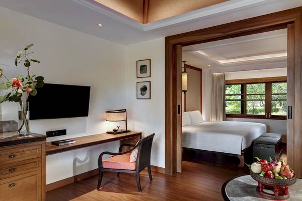 Innenansicht eines Hotelzimmers im Santiburi Koh Samui mit Schreibtisch, Bett und Früchten auf dem Tisch.