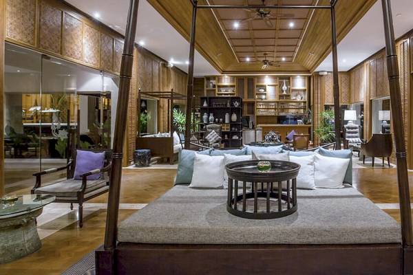Innenbereich des Santiburi Koh Samui Hotels mit einem großen Bett, Kissen, einem Tisch und Möbeln.