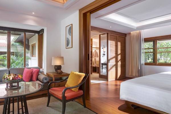 Schlafzimmer im Santiburi Koh Samui Hotel mit Bett, Couch, Tisch und Lampe.