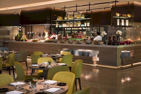 Innenbereich des Restaurants im Saadiyat Rotana Resort & Villas mit grünen Stühlen und Tischen.