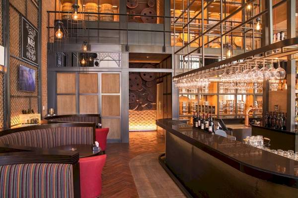 Innenansicht der Bar im Saadiyat Rotana Resort & Villas Hotel mit Sitzgelegenheiten und einer Theke voller Flaschen.