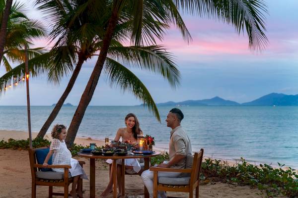 Familie genießt Abendessen am Strand im Santiburi Koh Samui Hotel.
