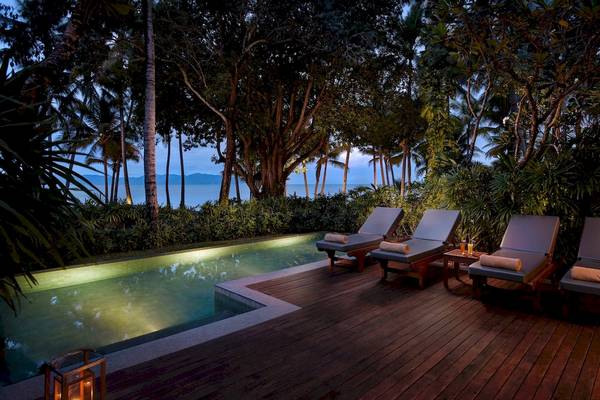 Pool-Lounge-Bereich im Santiburi Koh Samui Hotel mit vier Liegen und Meerblick.
