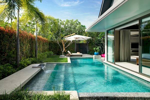 Außenbereich des Santiburi Koh Samui Hotels mit Swimmingpool, Sonnenliege und Sonnenschirm.