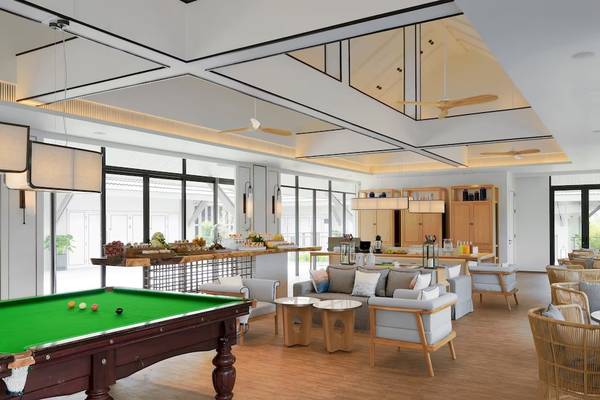 Loungebereich im Meliá Koh Samui mit grünem Pooltisch, weißen Möbeln und großen Fenstern.