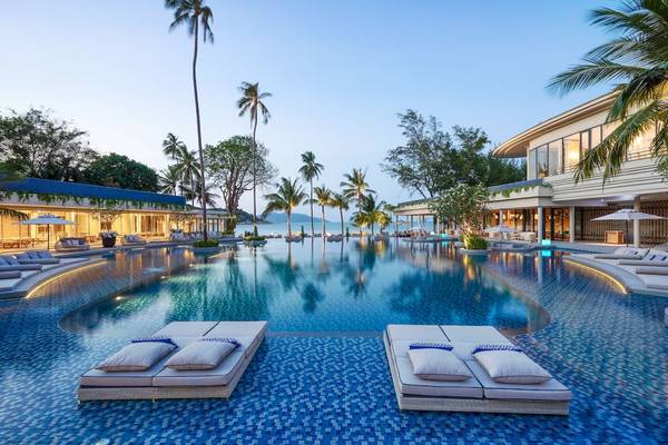 Pool-Loungebereich im Meliá Koh Samui mit zwei Loungebetten und Sonnenschirmen.