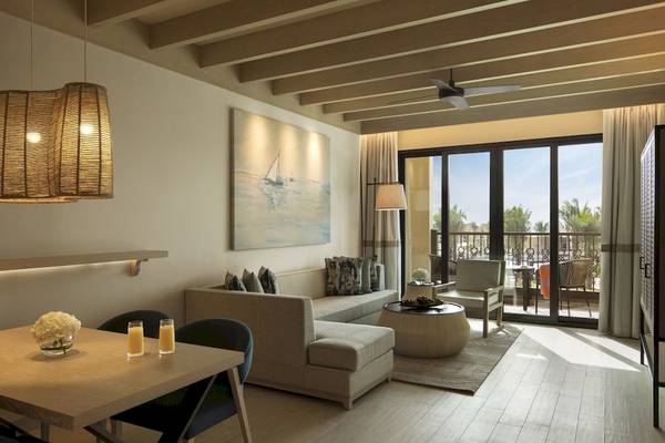 Wohnzimmer des Saadiyat Rotana Resort & Villas mit moderner Einrichtung, einem großen Sofa, einem Tisch, einer Lampe und einem Gemälde an der Wand.