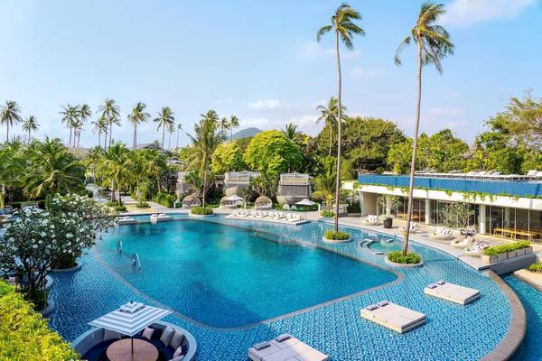 Außenbereich des Pools im Meliá Koh Samui Hotel mit Palmen und Loungemöbeln.