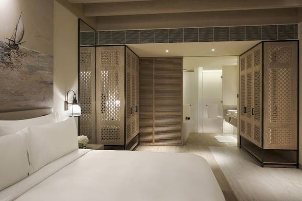 Innenansicht eines Zimmers im Saadiyat Rotana Resort & Villas mit Doppelbett, Badezimmer und Gemälde.