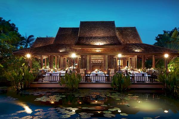 Außenansicht des Bo Phut Resort & Spa bei Nacht mit umliegenden Teich und Pflanzen.