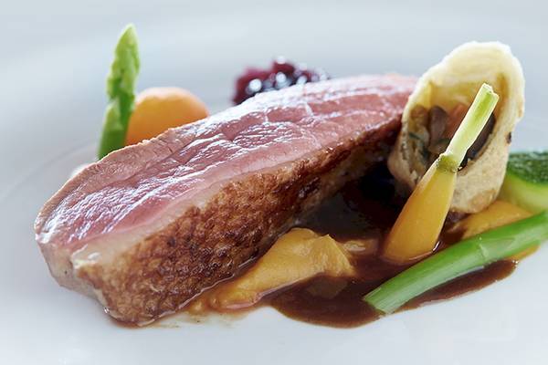 Ein Gericht im Bo Phut Resort & Spa mit gebratenem Fleisch, Gemüse und Soße auf einem weißen Teller.