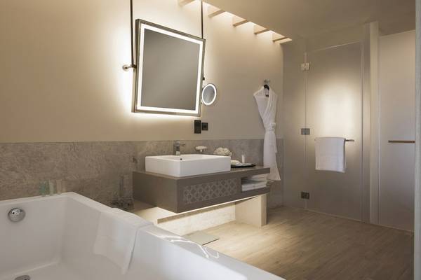 Badezimmer im Saadiyat Rotana Resort & Villas mit Badewanne, Waschbecken und Spiegeln.